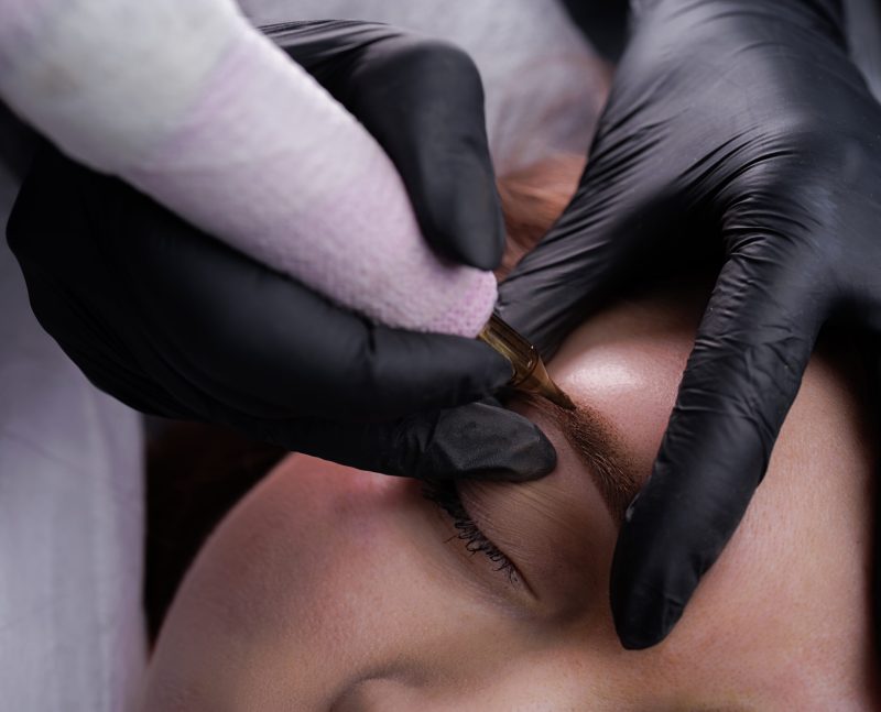 Technique of air application of permanent makeup on the model's eyebrows. PMU Procedure, Permanent Eyebrow Makeup.